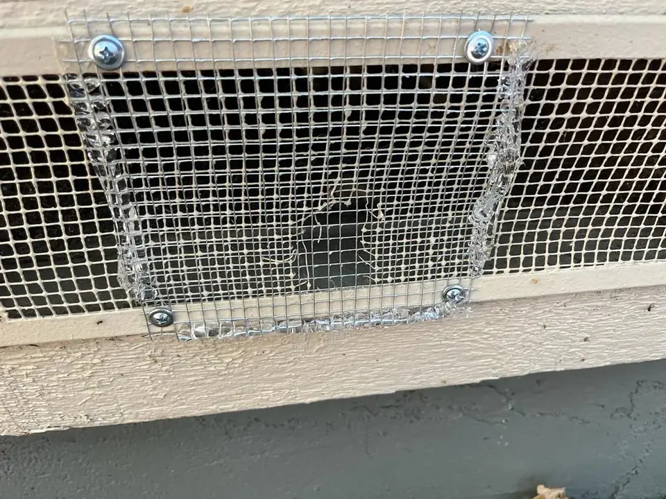 Vent covered with a new steel mesh panel, screwed in at the corners