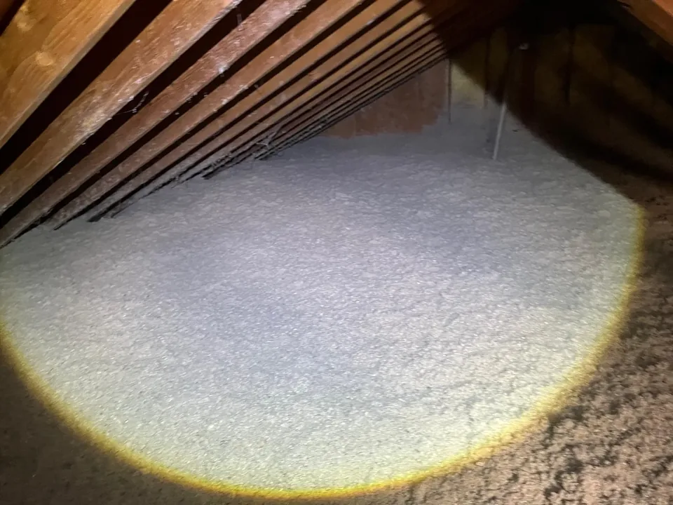 Attic floor covered in an even layer of gray blown-in cellulose insulation
