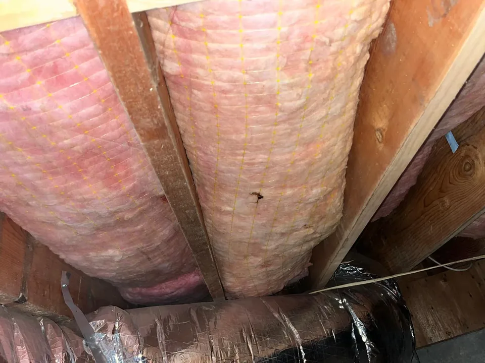 Batt insulation fitted snug between wooden rafters