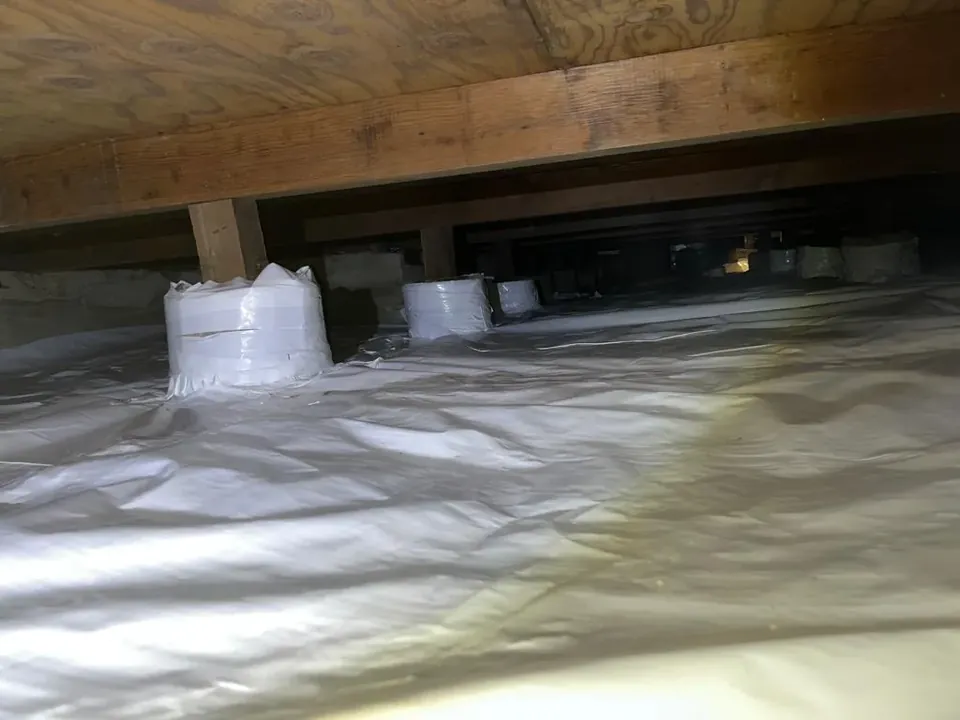 Clean crawl space after the work, with the ground covered in white sheeting