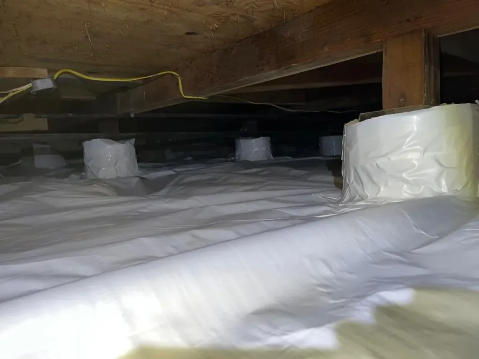 Long crawl space covered wall to wall with white vapor barrier