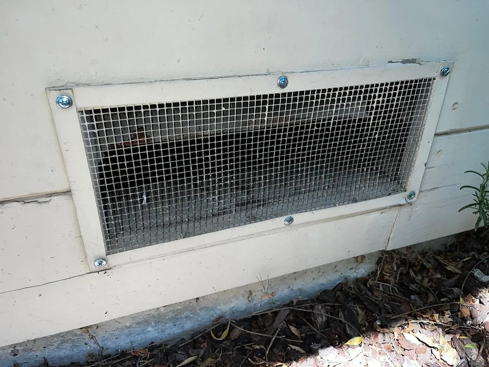Crawl space vent fully covered with galvanized steel mesh, screwed in on every side
